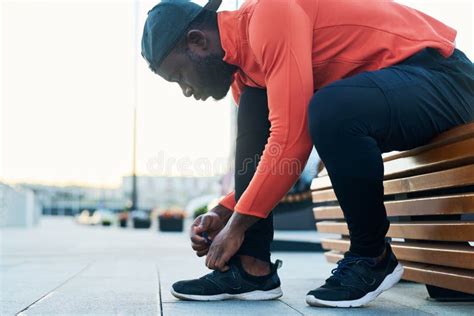 Side View Of African American Runner Bending Over Sneaker While Tying