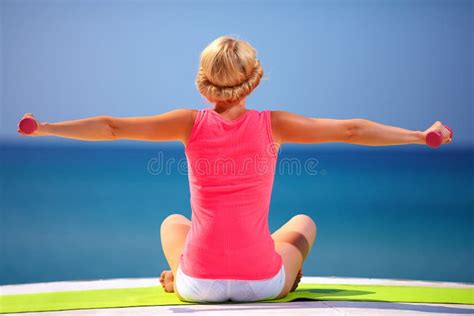 Young Woman Doing Exercises With Hand Weights On The Beach Stock Photo