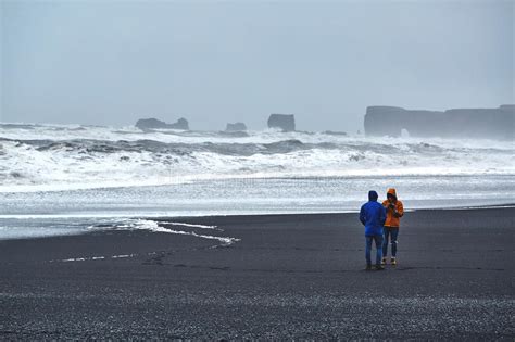 People Walks On Black Sand Beach Of Reynisfjara In South Of Iceland
