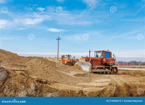 An Old Orange Bulldozer Performs Work To Level The Sandy Soil Stock
