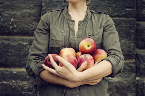 Midsection Of Woman Holding Apples While Standing Against Wall Stock Photo