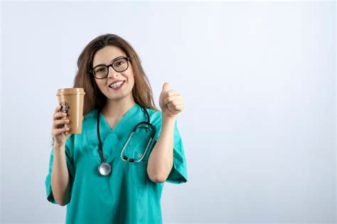 Hermosa Joven Enfermera Con Estetoscopio Sosteniendo Una Taza De Café Y