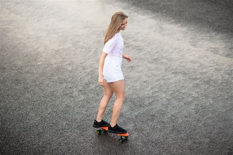 Young Beautiful Blonde Girl Riding Bright Skateboard On The Bridge
