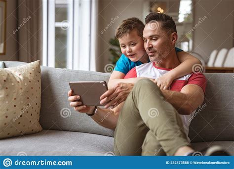 Caucasian Father And Son Using Digital Tablet On The Couch At Home