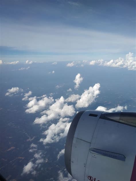 The View From An Airplane Window Shows Clouds In The Sky And Below It