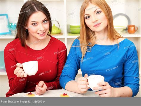 Two Girl Friends Talk And Drink Tea In Kitchen Stock Photography