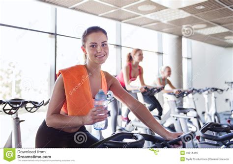 Group Of Women Riding On Exercise Bike In Gym Stock Photo