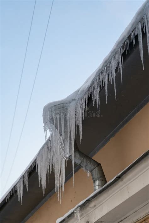 Big Frozen Icicles Dangerously Hanging From Building Edge On Cold