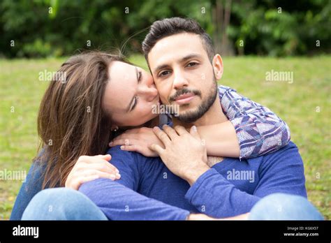 Young Beautiful Couple Sitting Outside In Park And Hugging Each Other