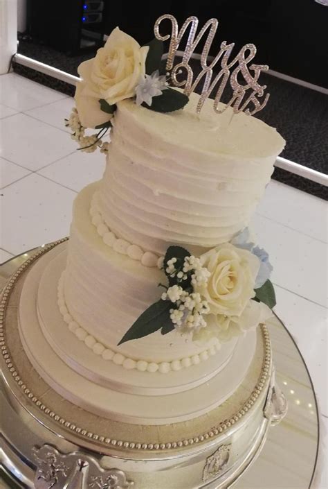 2 tier buttercream wedding cake with artificial flowers