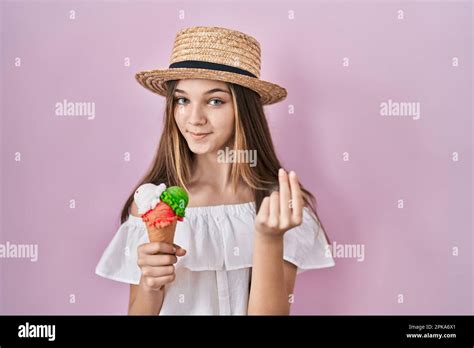 Teenager girl holding ice cream doing money gesture with hands, asking