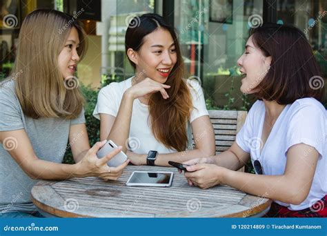 Cheerful Asian Young Women Sitting In Cafe Drinking Coffee With Friends And Talking Together