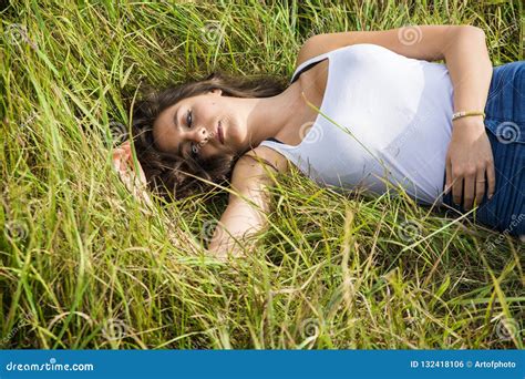 Smiling Brunette Laying On Grass In Sunlight