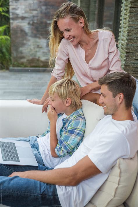 View Smiling Mother With Son And Husband Looking At Laptop By Stocksy