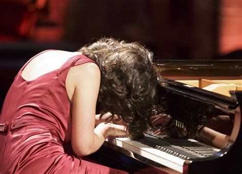 A Woman In A Red Dress Is Playing The Piano With Her Head Down And