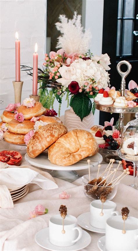 A Table Filled With Pastries And Desserts On Top Of White Cloth Covered