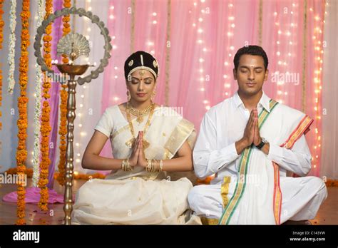 Bride and bridegroom in traditional South Indian dress praying at
