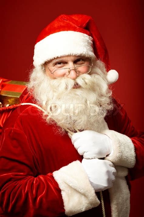 Portrait Of Happy Santa Claus Holding Sack With Ts And Looking At