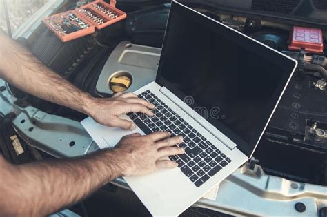 Professional Car Mechanic Working In Auto Repair Service Using Laptop