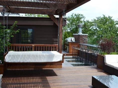 An Outdoor Living Area With Couches Table And Grill On The Back Deck