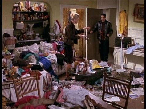 Two People Standing In A Messy Room Full Of Clutter And Clothes On The Floor