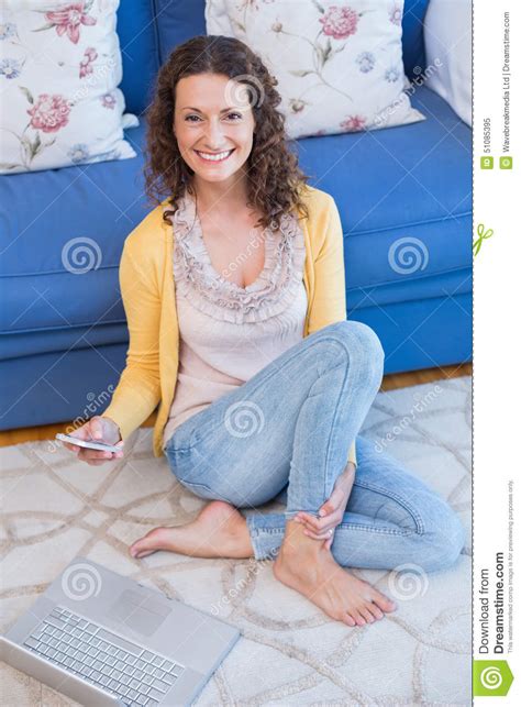 pretty brunette sitting on the floor and using her smartphone stock image image of