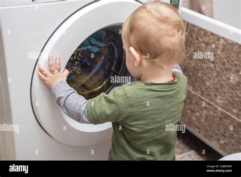 Child Boy Is Looking Into The Washing Machine Baby Boy Interested In