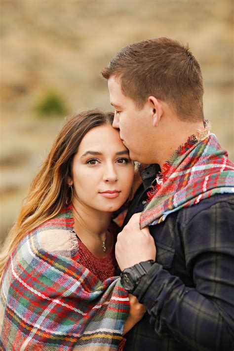 fall engagement session fiance couple kissing head plaid blanket blue and green plaid