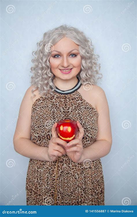 chubby blonde girl wearing summer dress and posing with big red apple on white background alone