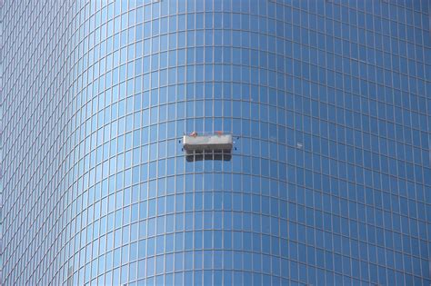 Free Stock Photo of Cleaners On Suspended Platform Of Building
