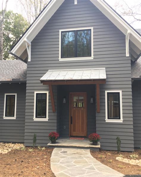 A Gray House With White Trim And Wooden Doors Is Shown In Front Of The