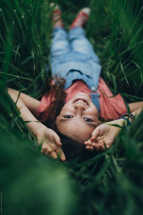 Smiling Little Girl Lying In Lawn By Dejan Ristovski Stocksy United