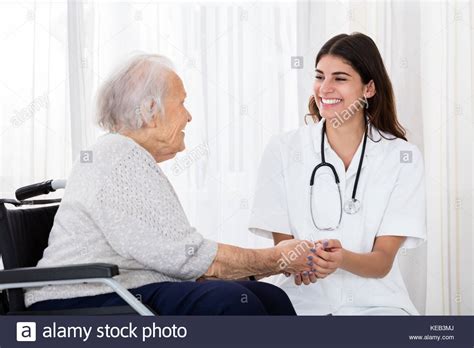 Happy Female Doctor Holding Hands Of Disabled Senior Patient On
