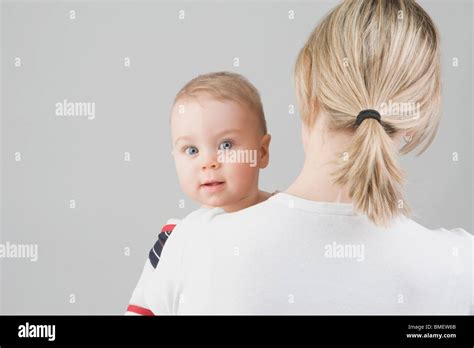 A Toddler Boy Looking Over His Mothers Shoulder Stock Photo Alamy