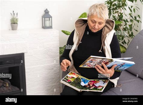 An elderly woman with nostalgia looks at old photos in a photo album or