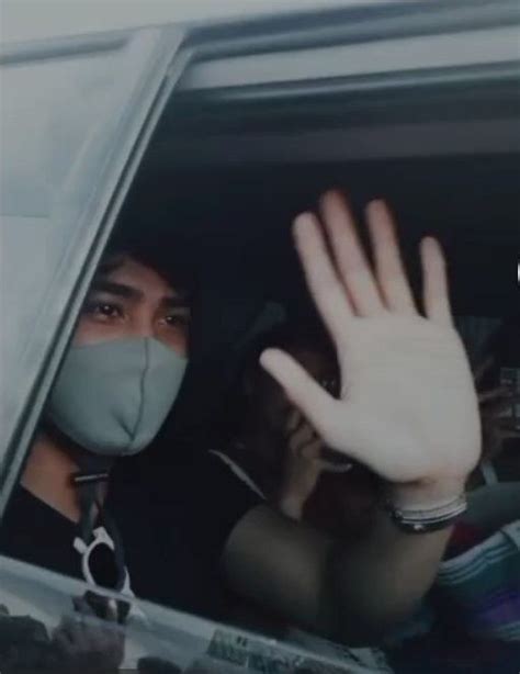A Person Wearing A Face Mask In A Car Waving To Someone With Their Hand