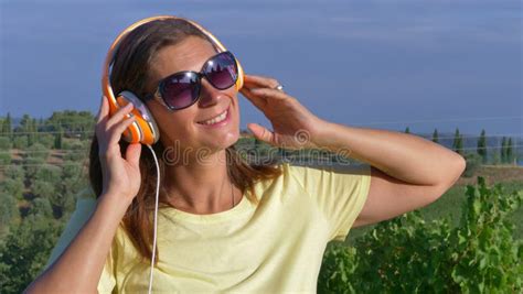 A Beautiful Woman Is Listening Music With Headphone Relaxing Near The