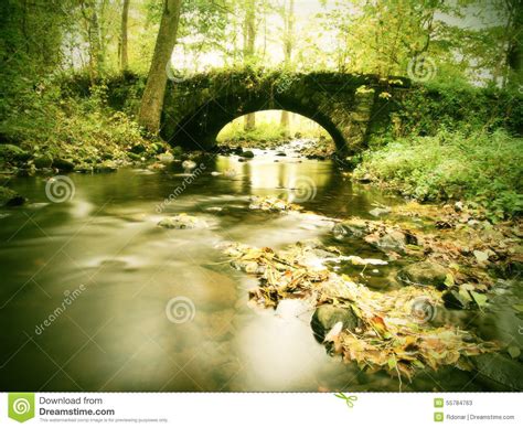 Old Stony Bridge Above Autumn River Water Of Stream Full Of Colorful