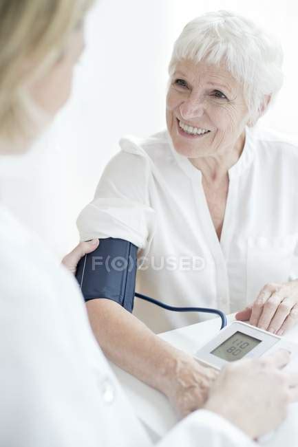 Female Doctor Taking Blood Pressure Of Senior Woman — Examining