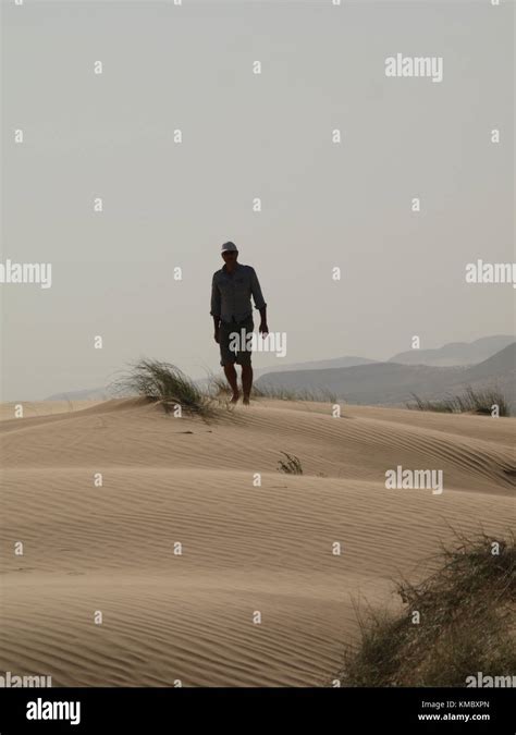 A Man Walking In The Desert On A Sand Dune Stock Photo Alamy