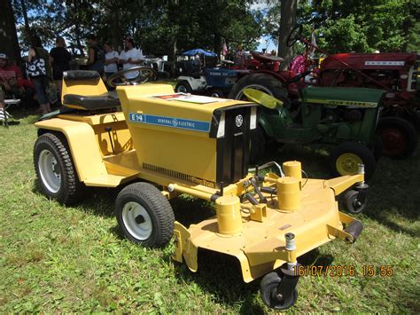 A Yellow Lawn Mower Sitting On Top Of A Lush Green Field Next To Other