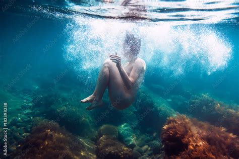 Naked woman with bubbles is underwater swimming in ocean ภาพถายสตอก Adobe Stock