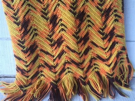 An Orange And Black Knitted Blanket With Fringes