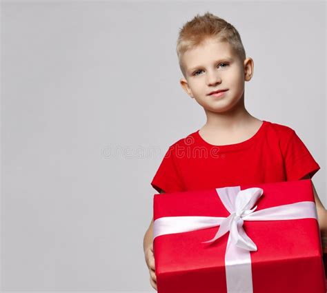 Portrait Of Smiling Kid Boy In Red T Shirt Holding Big Present Box With