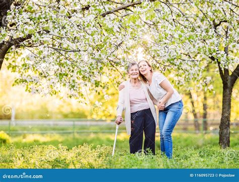 Elderly Grandmother With Crutch And Granddaughter In Spring Nature