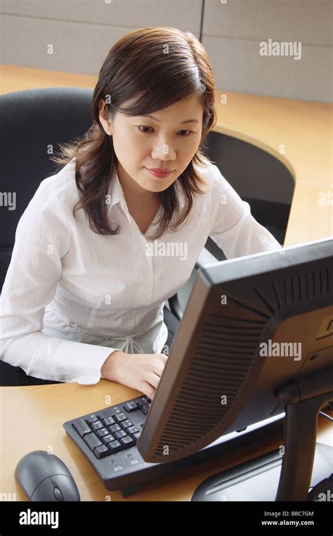Businesswoman Sitting In Office Cubicle Looking At Computer Stock