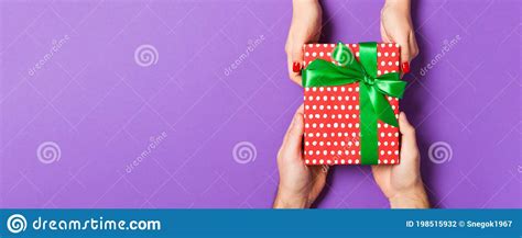 Top View Of Two People Sharing A Present On Colorful Background Holiday And Surprise Concept