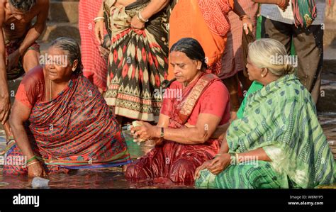 Three Indian Hindu Women Wearing Saris Perform An Early Morning Bathing Ritual In The River