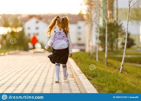 A Little Girl Goes To School Through The Park Along The Path Stock