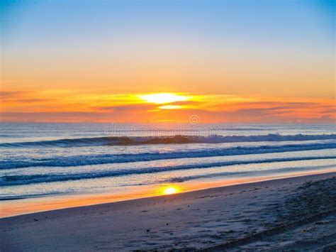 Wide Beach Image As Sun Rises Above Clouds On Horizon Stock Photo